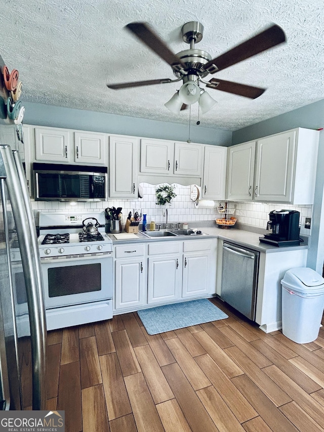 kitchen featuring white cabinets, appliances with stainless steel finishes, backsplash, and sink