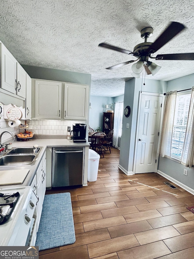 kitchen featuring tasteful backsplash, ceiling fan, sink, dishwasher, and white cabinetry