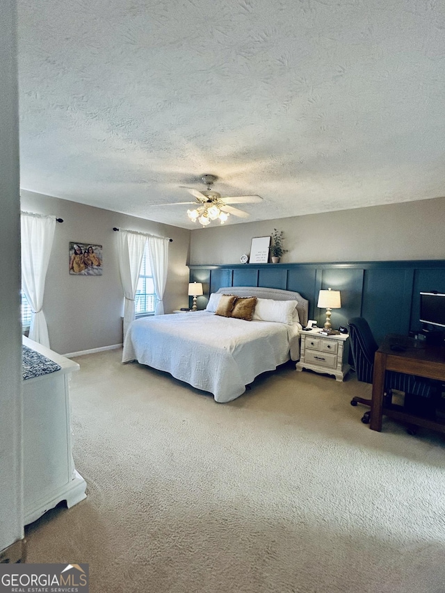 carpeted bedroom featuring ceiling fan and a textured ceiling