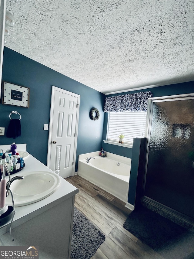 bathroom featuring vanity, shower with separate bathtub, wood-type flooring, and a textured ceiling