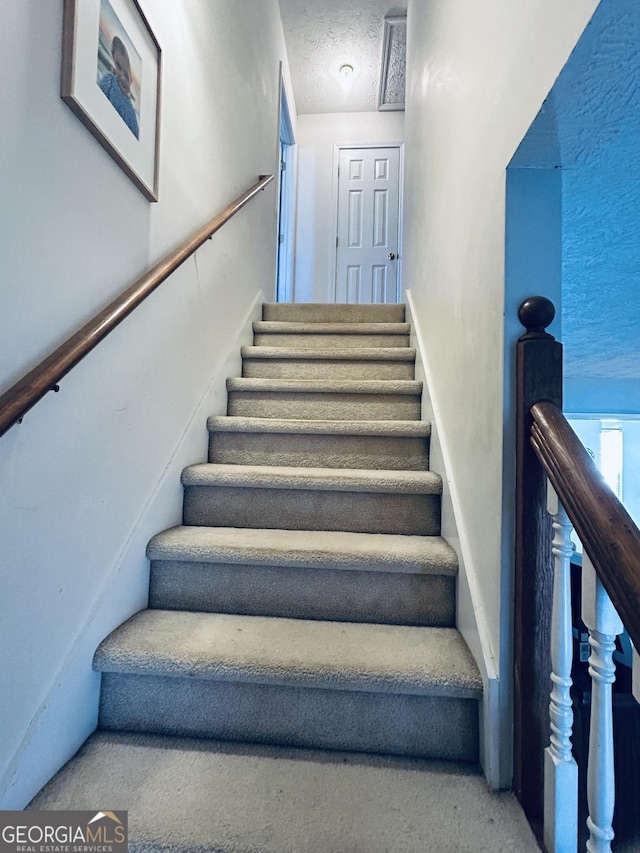 staircase with a textured ceiling