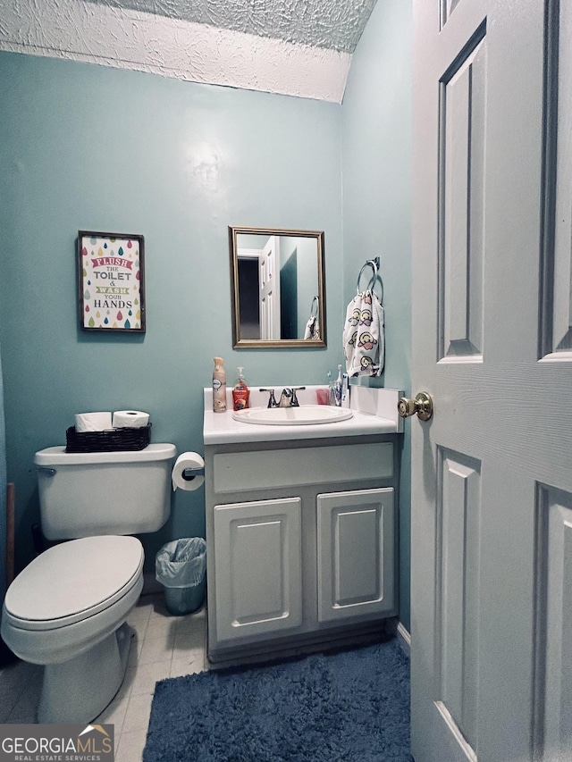 bathroom featuring vanity, a textured ceiling, tile patterned flooring, toilet, and lofted ceiling