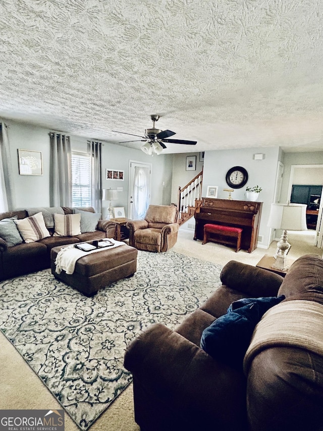 living room with a textured ceiling, carpet floors, and ceiling fan