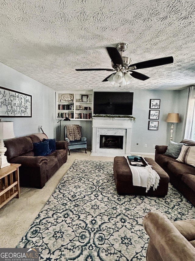 carpeted living room featuring a fireplace, ceiling fan, built in features, and a textured ceiling