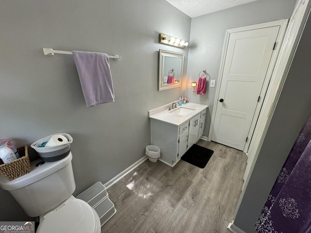 bathroom with hardwood / wood-style floors, vanity, a textured ceiling, and toilet