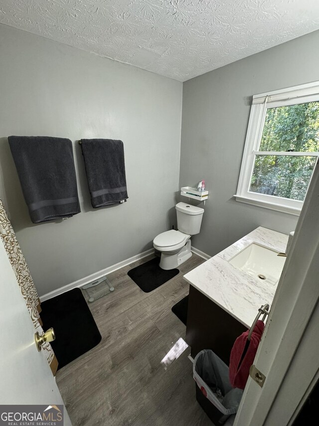 bathroom featuring wood-type flooring, vanity, a textured ceiling, and toilet