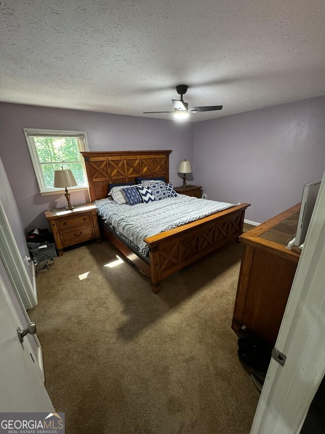 carpeted bedroom featuring ceiling fan and a textured ceiling