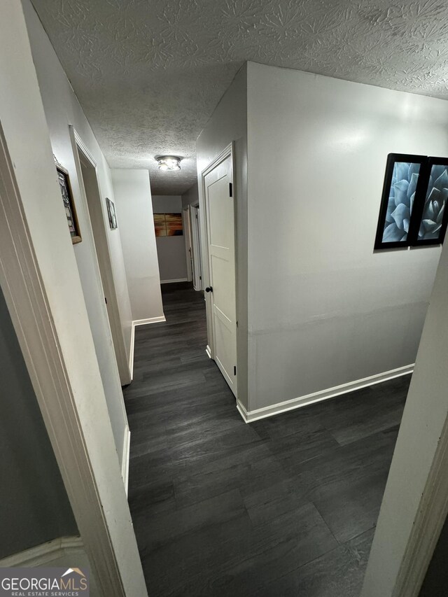 hall with dark hardwood / wood-style flooring and a textured ceiling