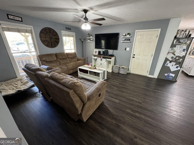 living room featuring dark hardwood / wood-style flooring, a textured ceiling, and ceiling fan