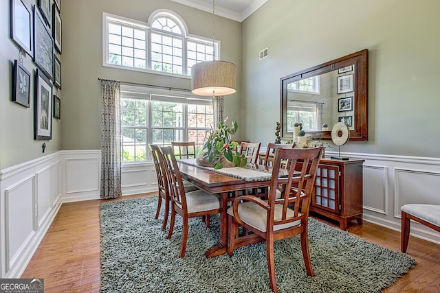 dining room with wood-type flooring, crown molding, and a wealth of natural light