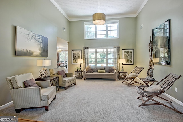 sitting room with carpet flooring, a towering ceiling, and ornamental molding