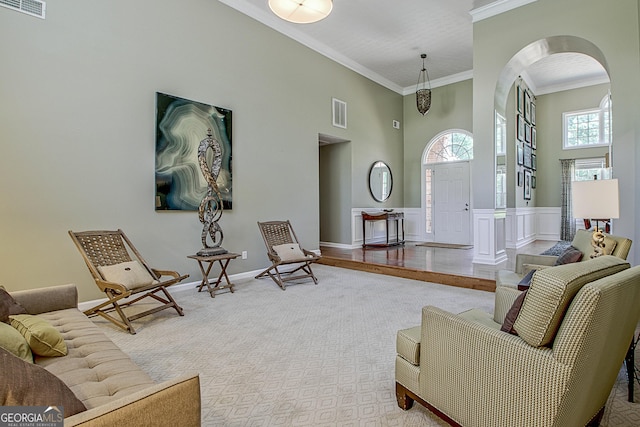 living room with a towering ceiling, carpet, and ornamental molding