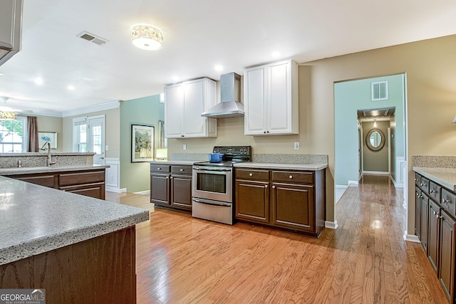 kitchen featuring dark brown cabinetry, wall chimney range hood, light hardwood / wood-style floors, white cabinetry, and stainless steel electric range