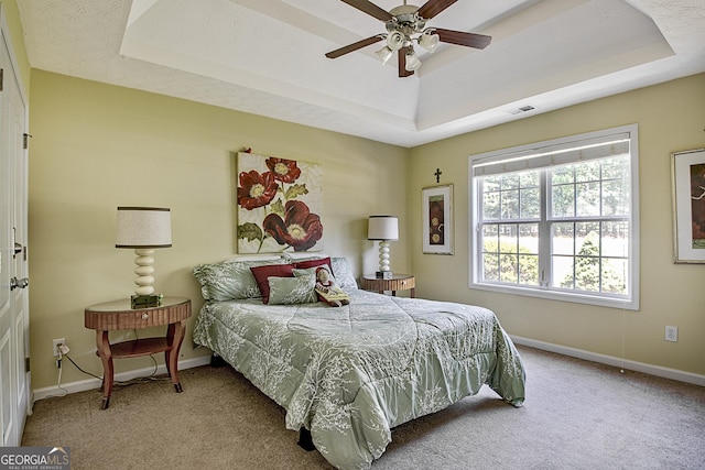 bedroom featuring ceiling fan, a raised ceiling, and light colored carpet