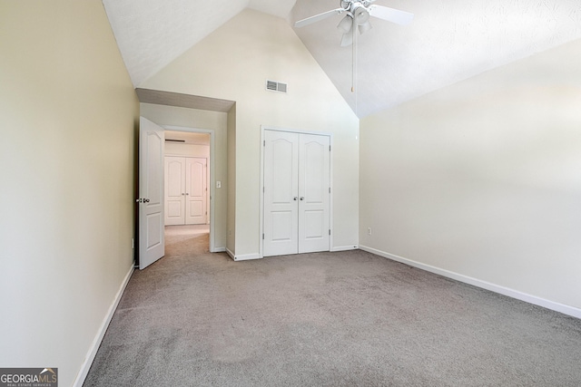 unfurnished bedroom featuring carpet floors, a closet, high vaulted ceiling, and ceiling fan