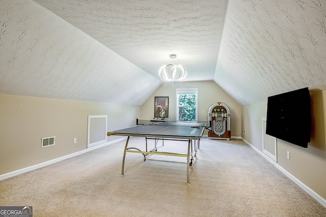 recreation room with vaulted ceiling, carpet floors, and a textured ceiling