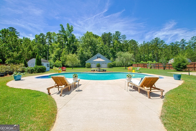 view of pool with a yard, an outbuilding, and a patio