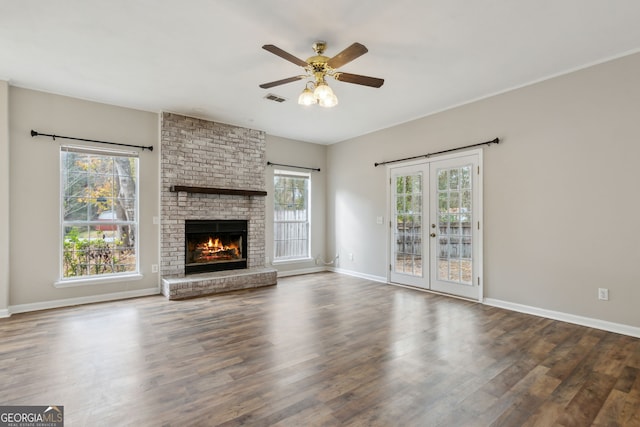 unfurnished living room featuring ceiling fan, a healthy amount of sunlight, dark hardwood / wood-style floors, and a brick fireplace