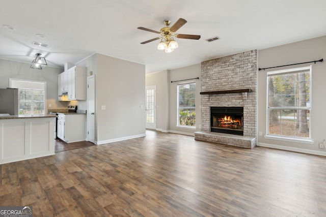 unfurnished living room featuring dark hardwood / wood-style flooring, a brick fireplace, and ceiling fan