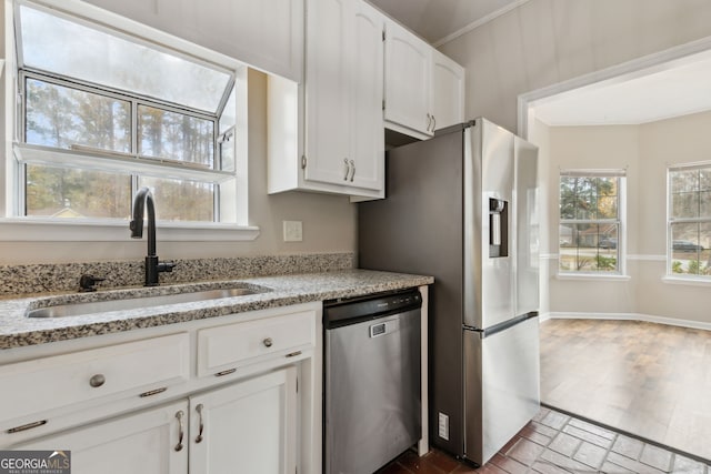 kitchen featuring white cabinets, sink, light stone countertops, and stainless steel appliances