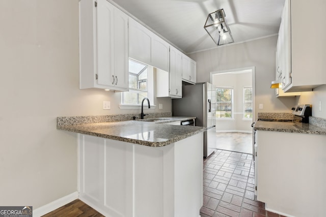 kitchen with kitchen peninsula, sink, white cabinets, and dark stone counters