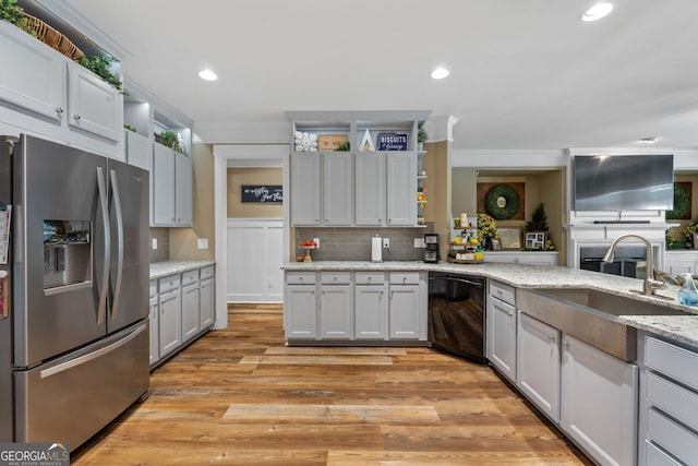 kitchen featuring light stone counters, sink, light hardwood / wood-style flooring, stainless steel fridge with ice dispenser, and black dishwasher