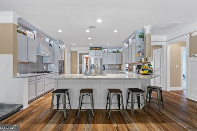 kitchen with a breakfast bar, sink, light stone countertops, tasteful backsplash, and dark hardwood / wood-style flooring