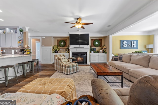 living room with dark hardwood / wood-style flooring, ceiling fan, and ornamental molding