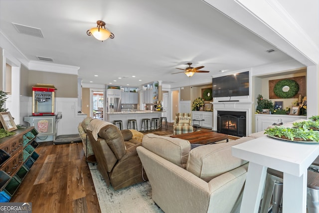 living room featuring dark hardwood / wood-style flooring, ceiling fan, and ornamental molding