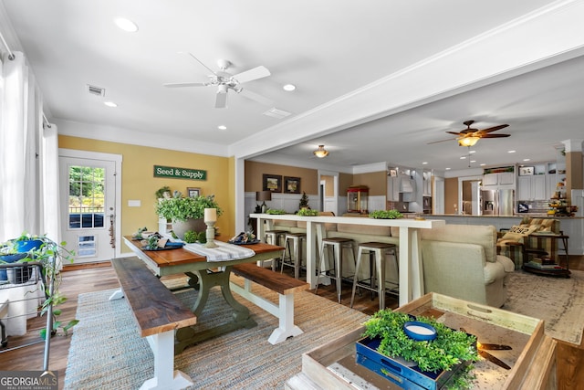 dining area with ceiling fan, wood-type flooring, and ornamental molding