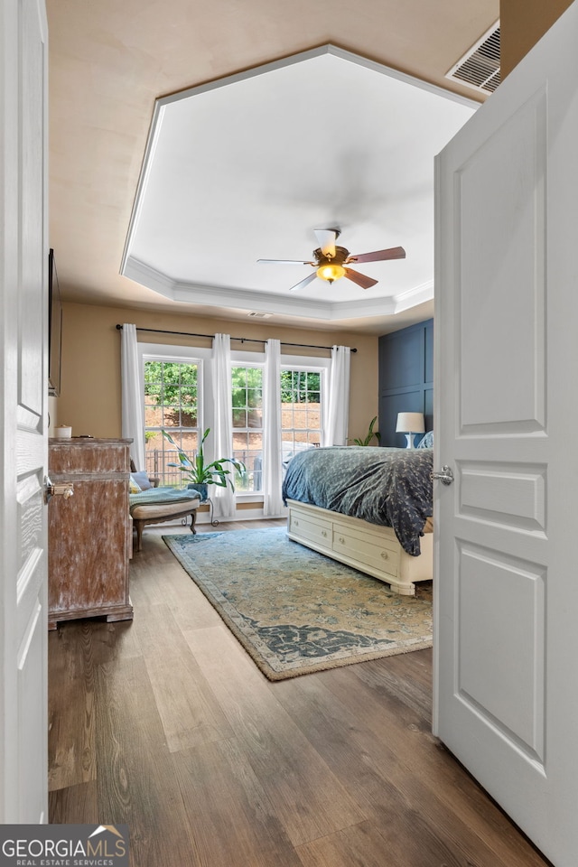 bedroom with hardwood / wood-style flooring, ceiling fan, and a tray ceiling