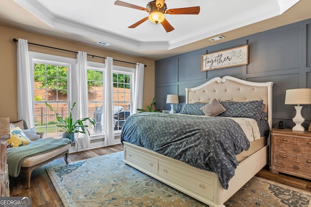 bedroom featuring a raised ceiling, multiple windows, ceiling fan, and access to outside