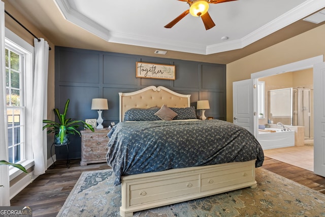 bedroom featuring ensuite bath, ornamental molding, a raised ceiling, ceiling fan, and hardwood / wood-style flooring