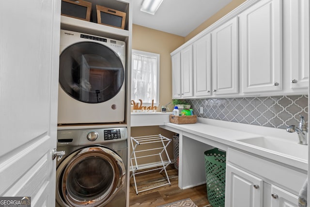 washroom with cabinets, stacked washer / dryer, dark wood-type flooring, and sink