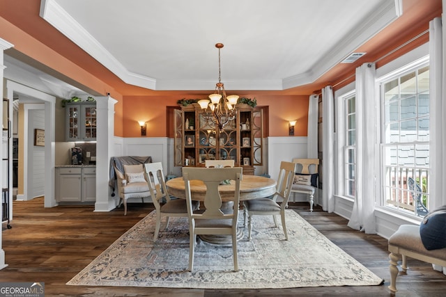 dining space with dark hardwood / wood-style flooring, ornamental molding, a tray ceiling, and a chandelier