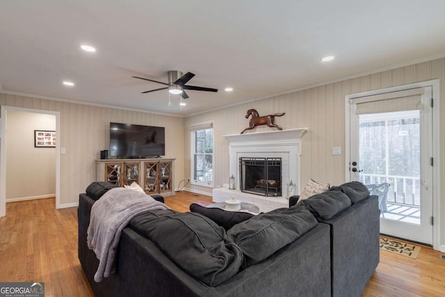 living room featuring ceiling fan, ornamental molding, and light hardwood / wood-style flooring