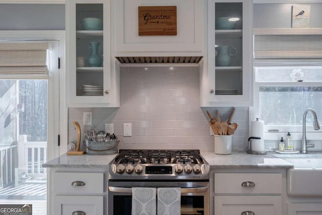 kitchen featuring light stone countertops, tasteful backsplash, sink, stainless steel gas stove, and white cabinetry