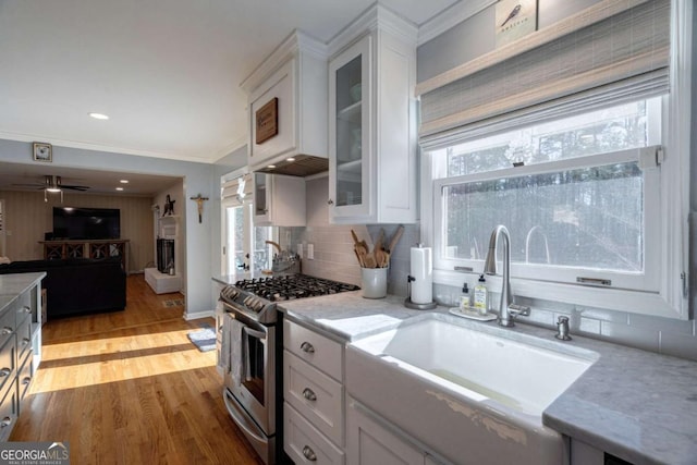 kitchen with light stone counters, sink, light hardwood / wood-style flooring, white cabinets, and stainless steel gas stove