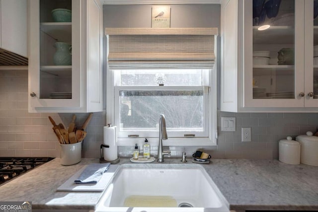 kitchen featuring white cabinetry, sink, tasteful backsplash, light stone counters, and black gas stovetop