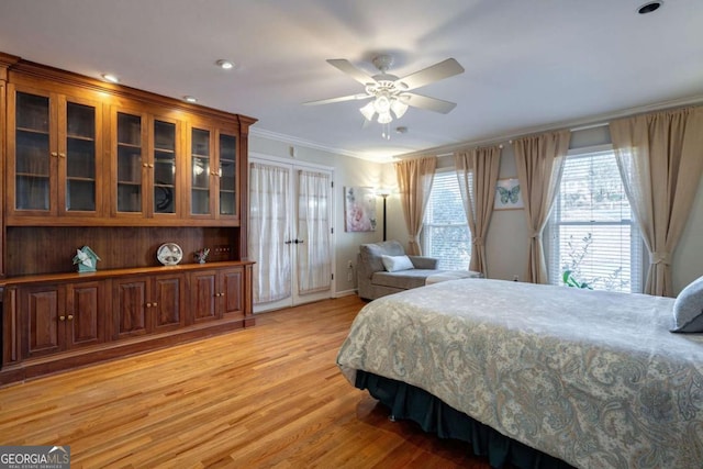 bedroom with ceiling fan, light wood-type flooring, and crown molding