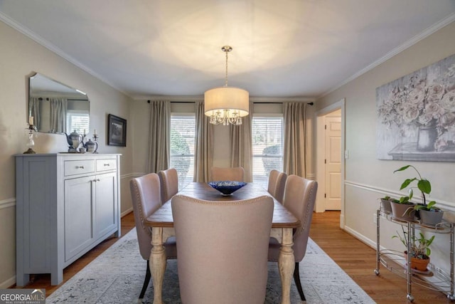 dining room featuring light wood-type flooring, ornamental molding, and a chandelier