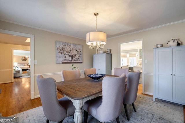 dining space featuring light wood-type flooring, an inviting chandelier, and crown molding