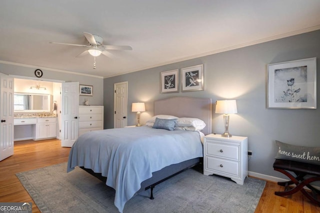 bedroom featuring ceiling fan, light hardwood / wood-style floors, ornamental molding, and connected bathroom