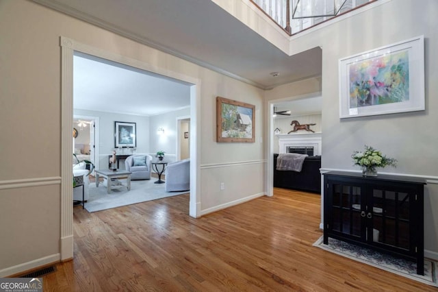 hall with wood-type flooring and ornamental molding