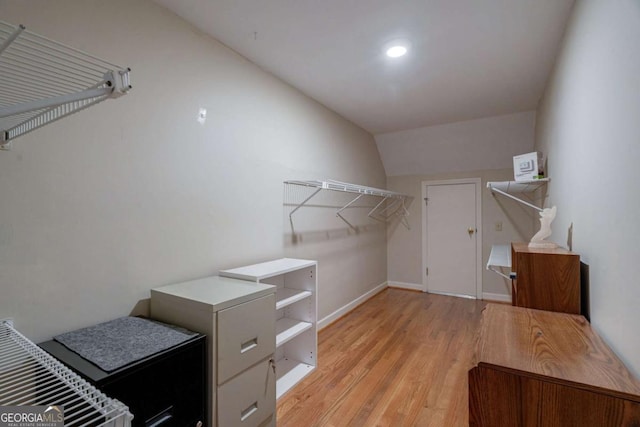 spacious closet with light hardwood / wood-style floors and vaulted ceiling