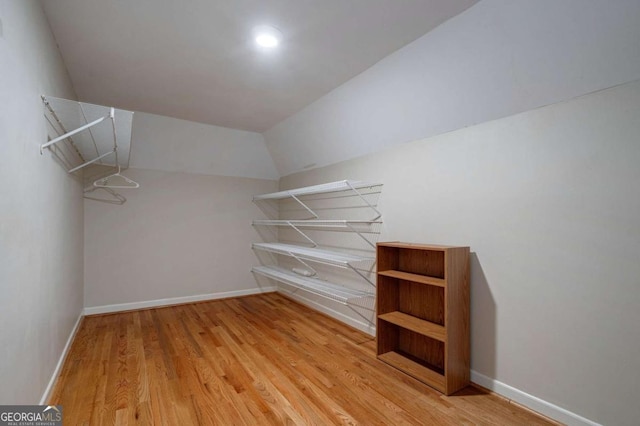 spacious closet featuring light hardwood / wood-style floors and lofted ceiling