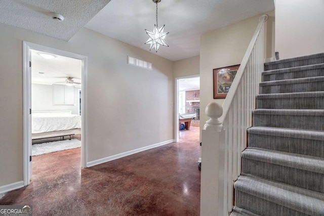 stairway with a textured ceiling, concrete floors, and a notable chandelier