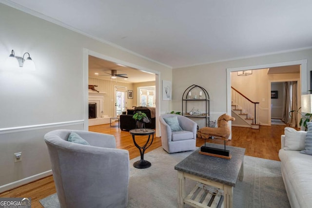 living room with hardwood / wood-style flooring, ceiling fan, and ornamental molding