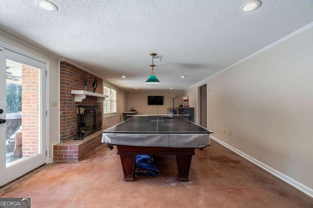 game room featuring pool table, ornamental molding, a textured ceiling, and a brick fireplace