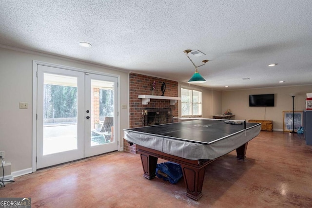 recreation room with a brick fireplace, concrete flooring, a textured ceiling, and french doors